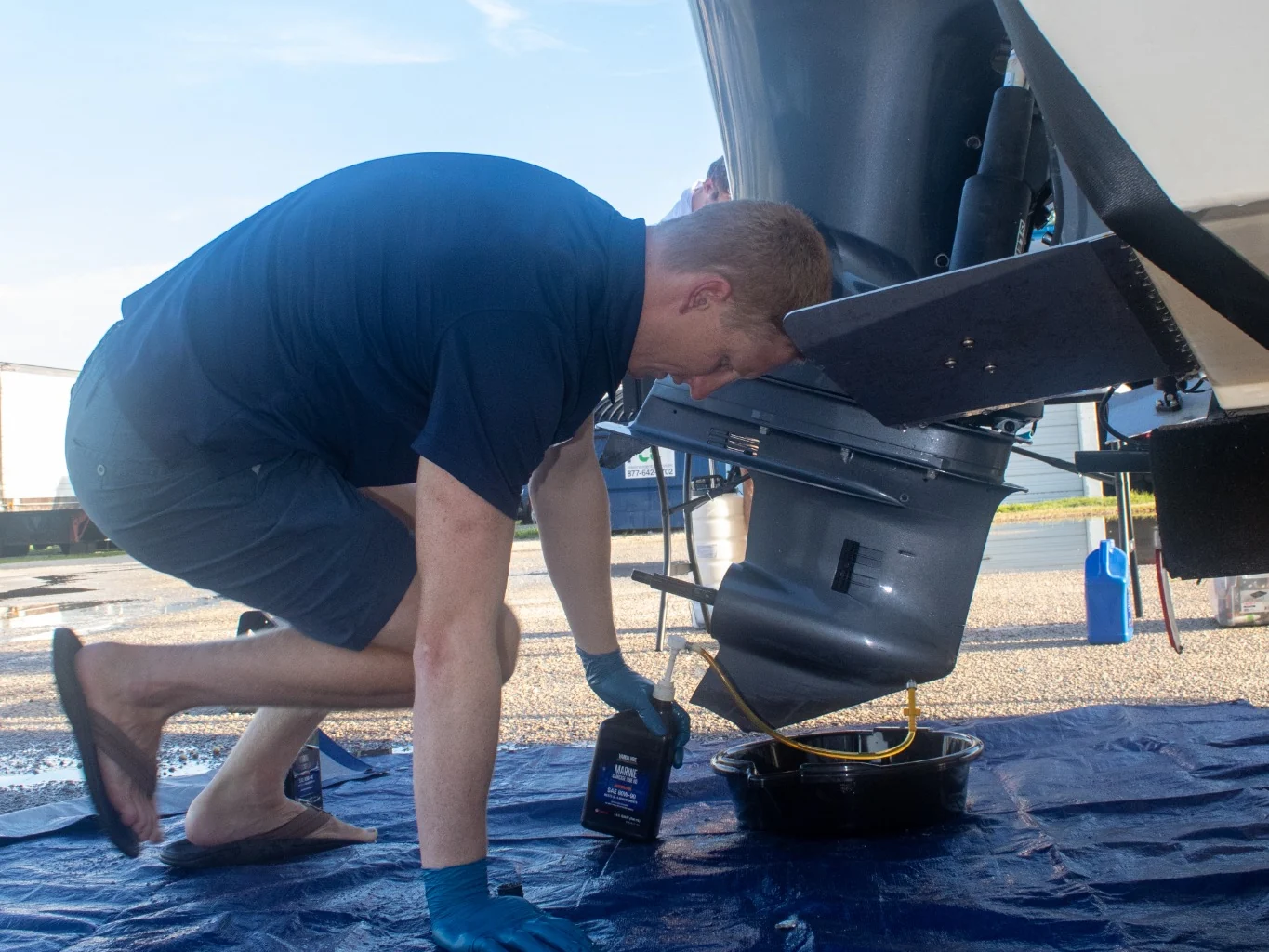 Outboard Pit Crew technician servicing lower-unit gear oil during 100-hour maintenance